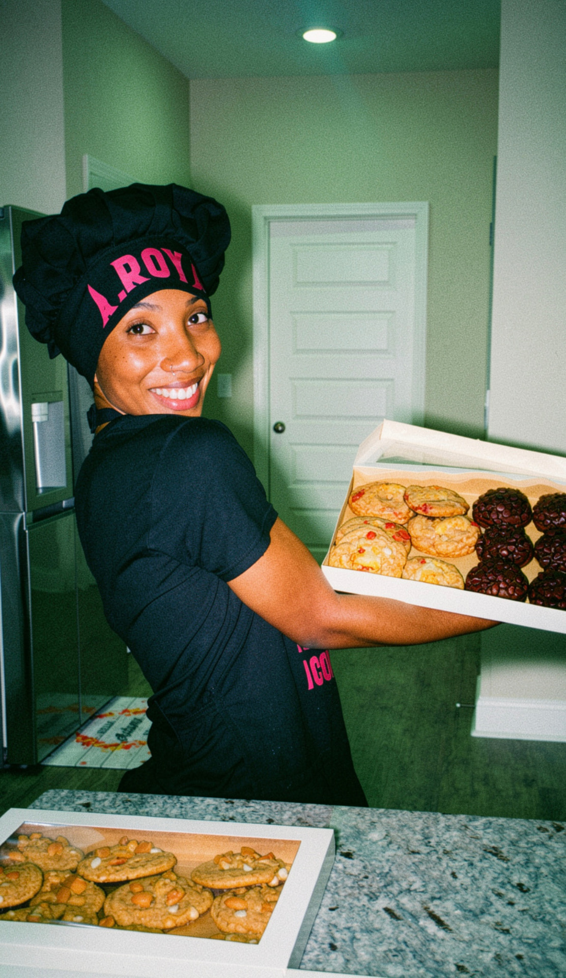 Founder Asia Royal smiling while holding a tray of freshly baked gourmet cookies